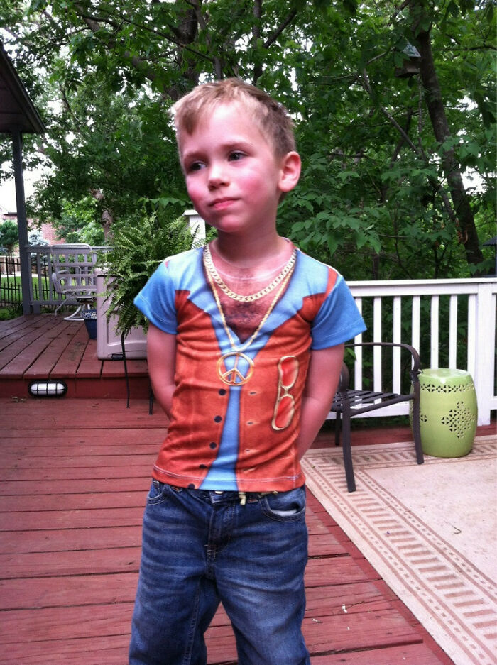 A young boy wearing a T-shirt with a printed vest, peace sign, and fake chest hair, a hilariously bad fashion crime.