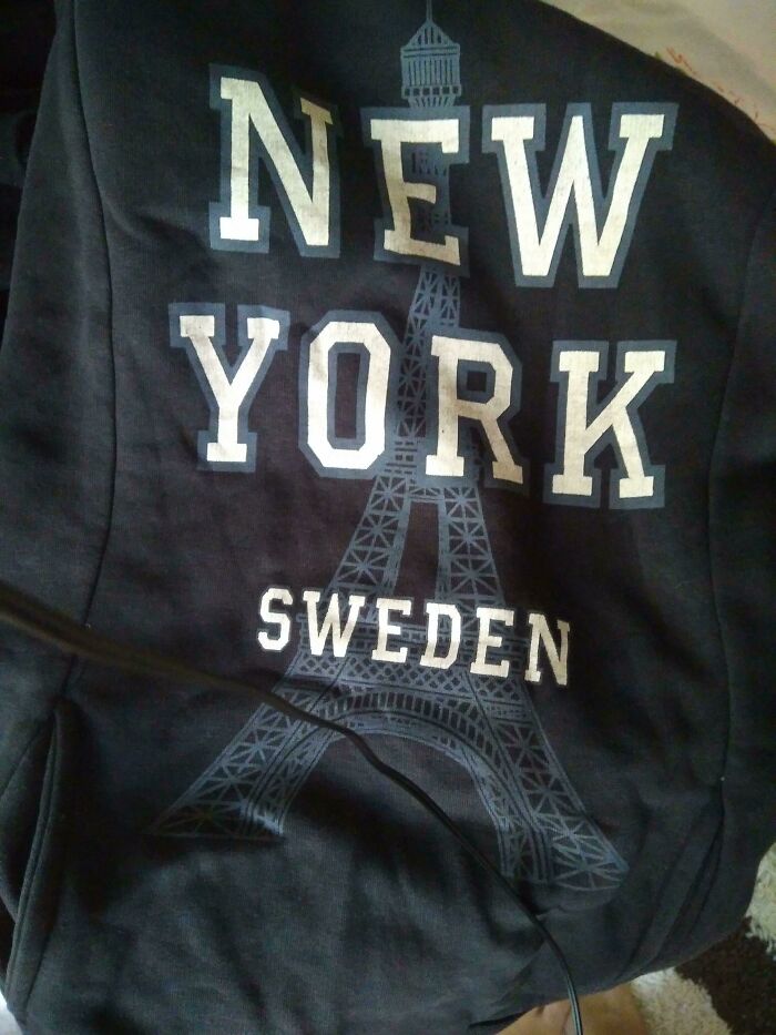 A black sweatshirt with the text 'NEW YORK SWEDEN' and an Eiffel Tower graphic, a hilariously bad fashion crime.