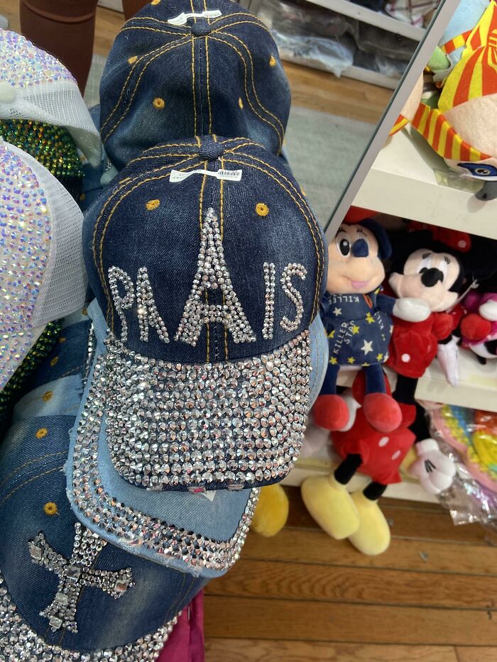A denim baseball cap with PAIS and the Eiffel Tower made of sparkling rhinestones, a hilariously bad fashion crime.