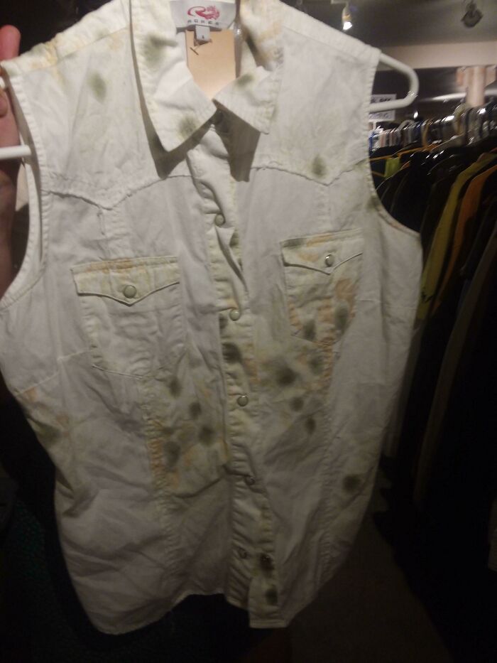 A white sleeveless shirt with hilariously bad fashion crime stains that look like mold.