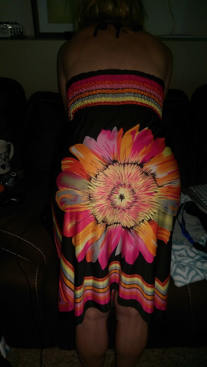 A person wearing a ridiculously bad fashion crime dress with a large, bright floral pattern on the buttocks and stripes.