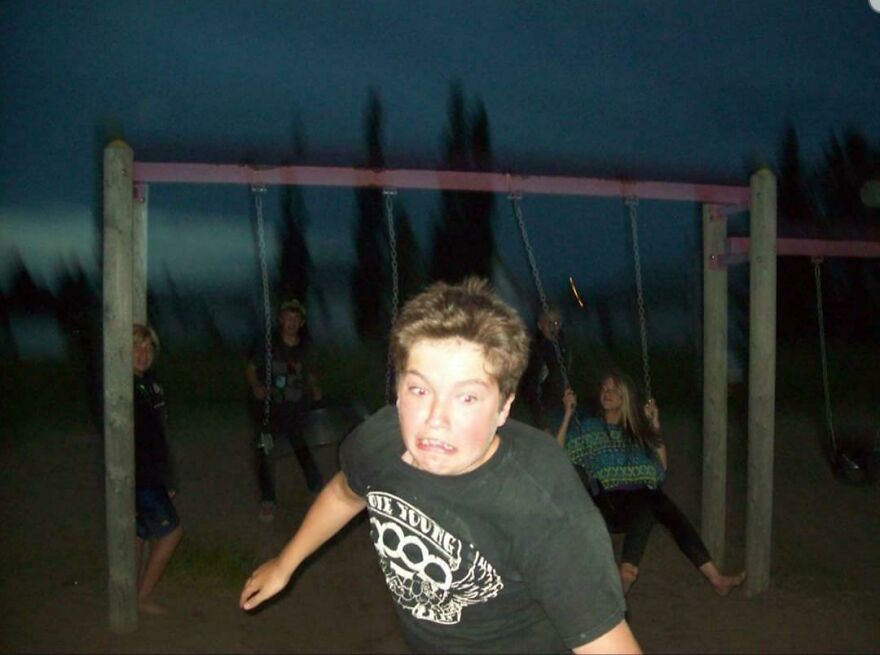 A blurry image captures a funny fail with a young boy making a goofy face at a playground with friends.