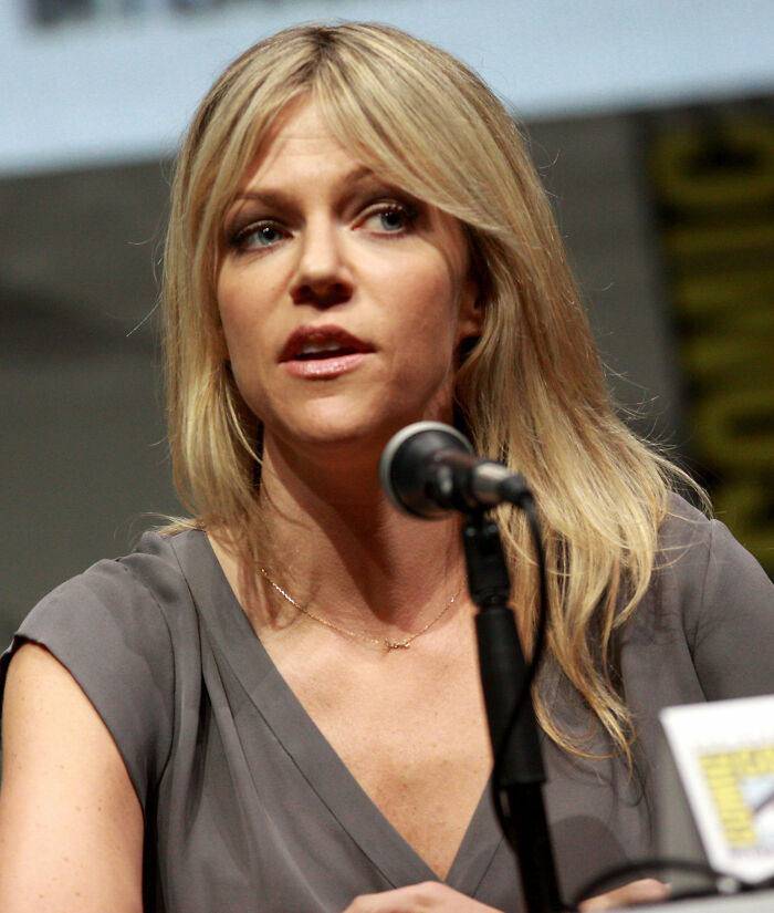 Kaitlin Olson with blonde hair and a gray top speaking into a microphone. Learn about Kaitlin Olson's career highlights.