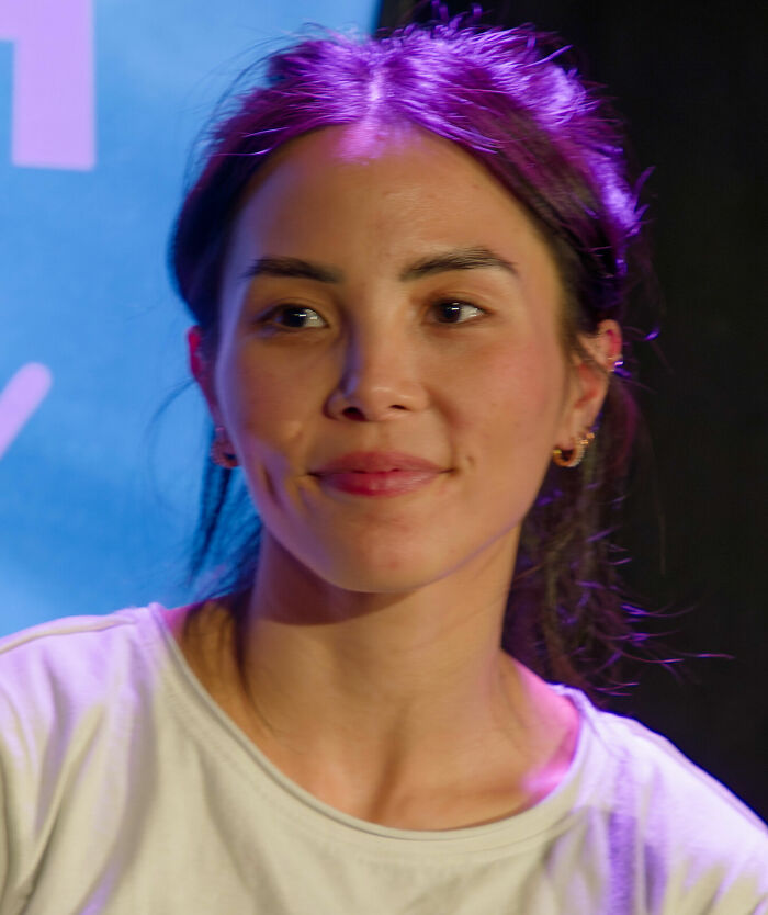 Anna Akana with purple-tinted hair, smiling slightly, capturing her bio and career highlights.