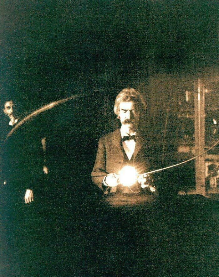 Beautiful historical photo of Mark Twain holding a glowing light source in a dimly lit room.