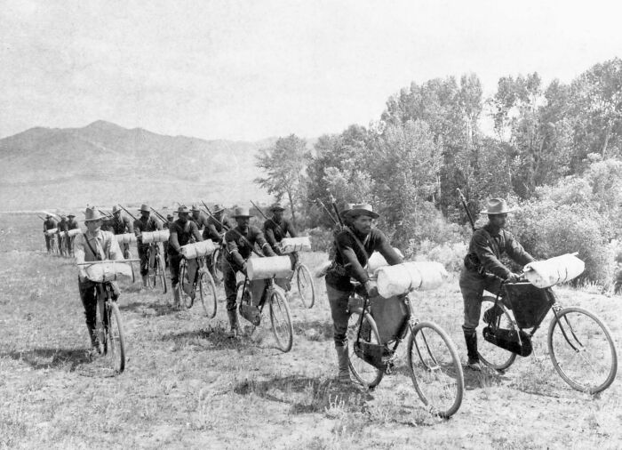 Interesting historical photo of soldiers on bicycles with gear, cycling through a field.