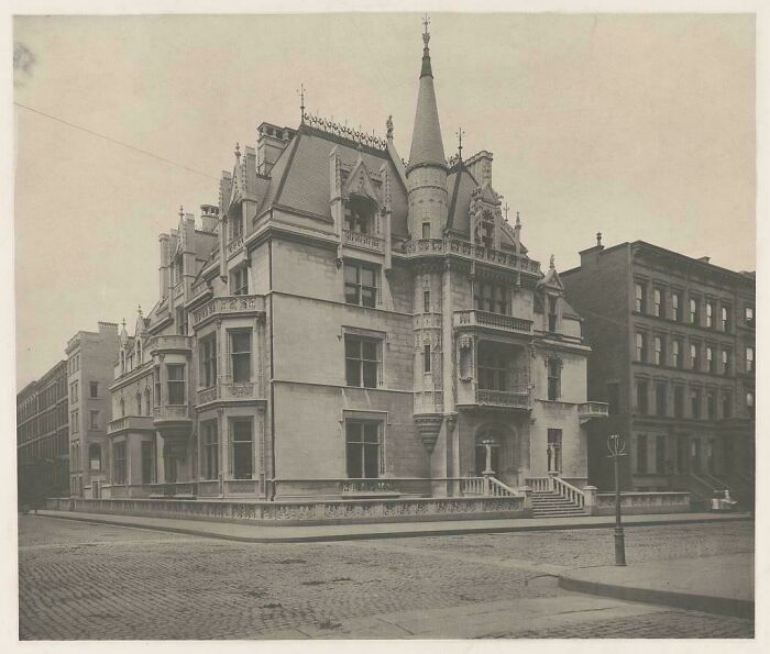 Beautiful photo from history of a grand, ornate mansion on a corner with a cobblestone street