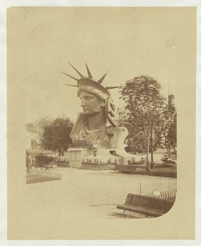 An interesting historical photo of the Statue of Liberty's head on display in a park, capturing a beautiful moment.