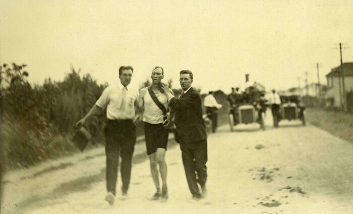 A beautiful historical photo showing an exhausted runner being supported by two men during an old marathon race.