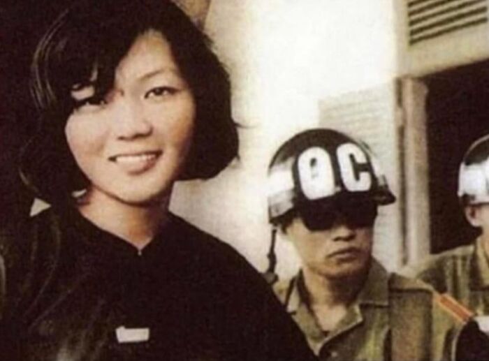 An interesting historical photo of a woman smiling, with soldiers in the background, offering a glimpse into history.