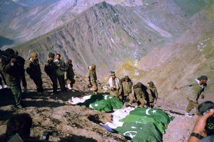 Soldiers with flags in a rugged mountainous landscape, a heartbreaking photo from history.