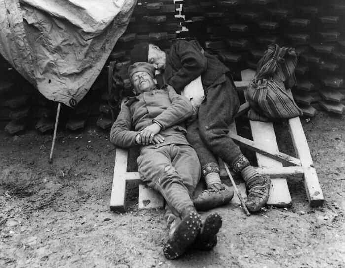 Two figures resting on a makeshift bed, a heartbreaking photo from history revealing human struggle.