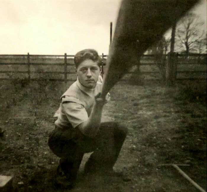 Man kneeling outdoors, holding an object, a historical photo that is interesting.