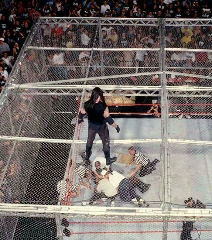 The Undertaker standing atop the steel cage with Mankind below, an interesting photo from history.