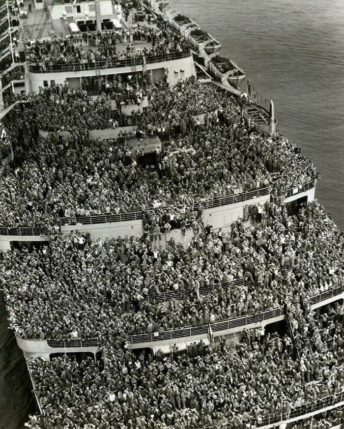 A beautiful historical photo of a crowded ship filled with people on its decks.