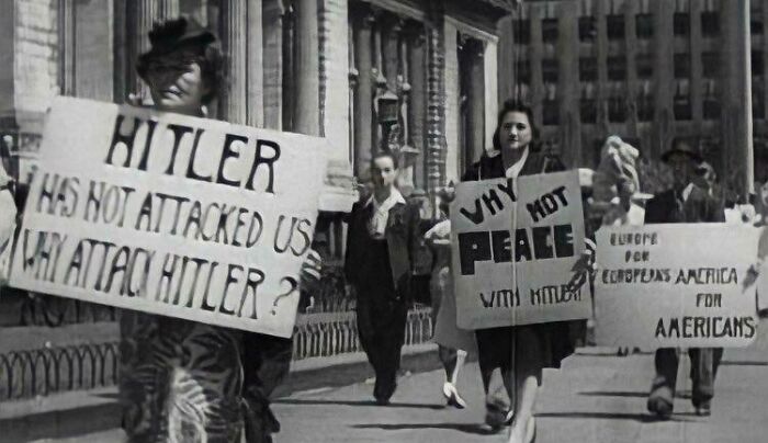 A historical photo showing people protesting against war, holding signs that read 'Why not peace'.
