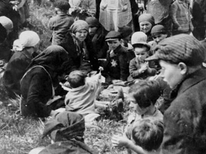 An interesting, heartbreaking photo from history of people gathered outdoors, some wearing a Star of David.