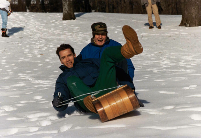A candid, interesting photo from history of two men sledding in snow, smiling.