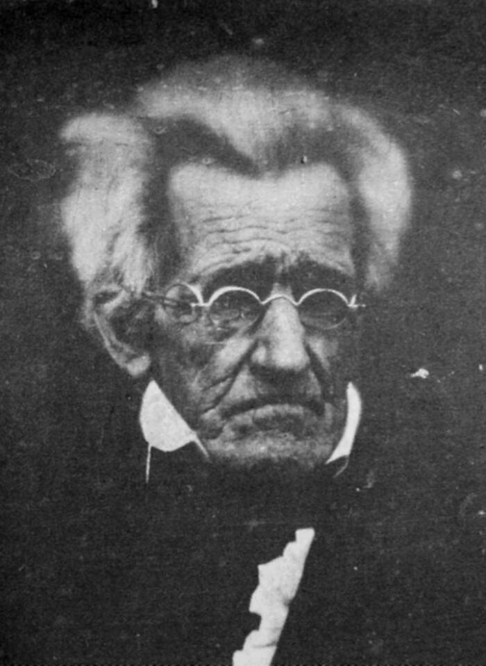 A close-up, black and white portrait of an elderly man with round glasses, a beautiful photo from history.