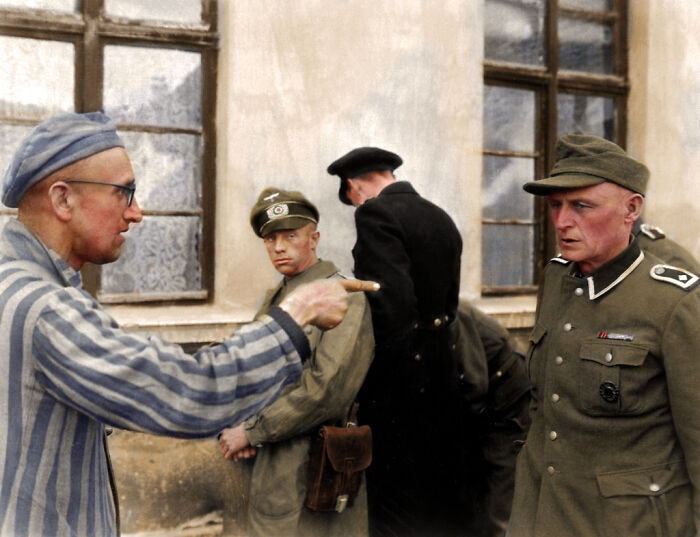 A man in a striped uniform points intensely at a N**i officer, a heartbreaking historical photo.