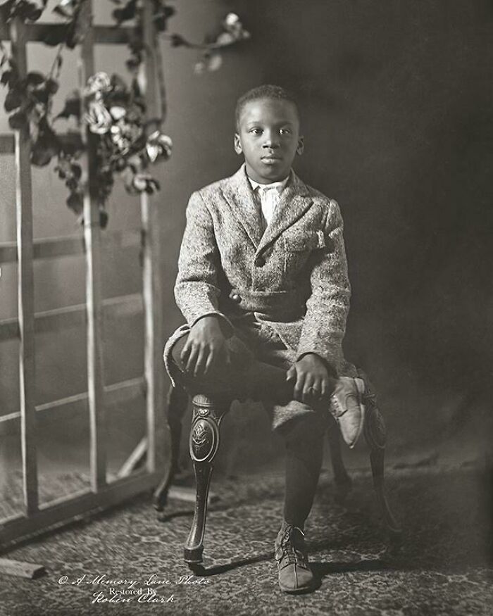 A young boy in a suit sitting on an ornate chair, a poignant historical photo.