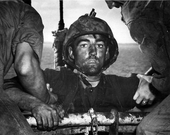 A heartbreaking photo from history shows a soldier being helped, his face covered in grime, looking exhausted and disoriented.