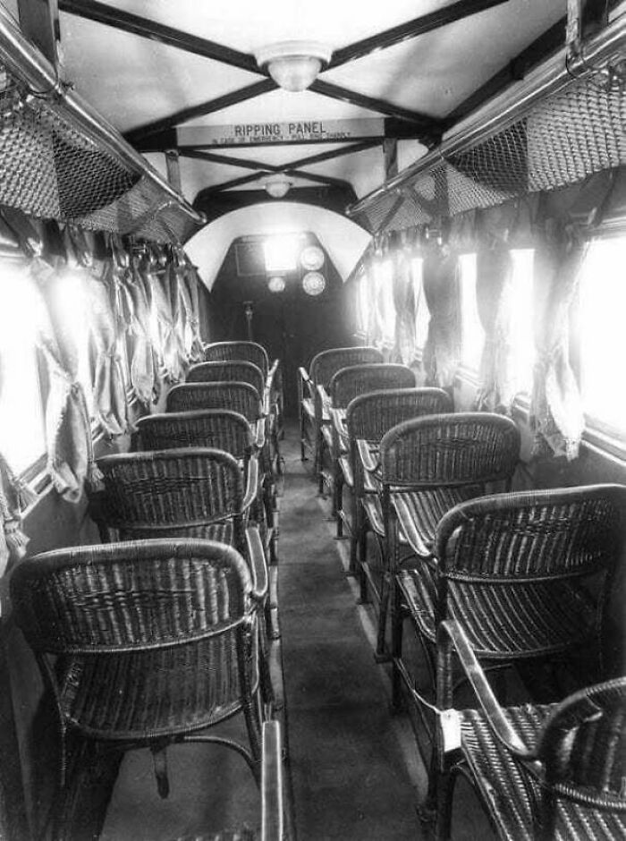 An interesting photo from history showing the interior of an early passenger airplane with rows of wicker seats.