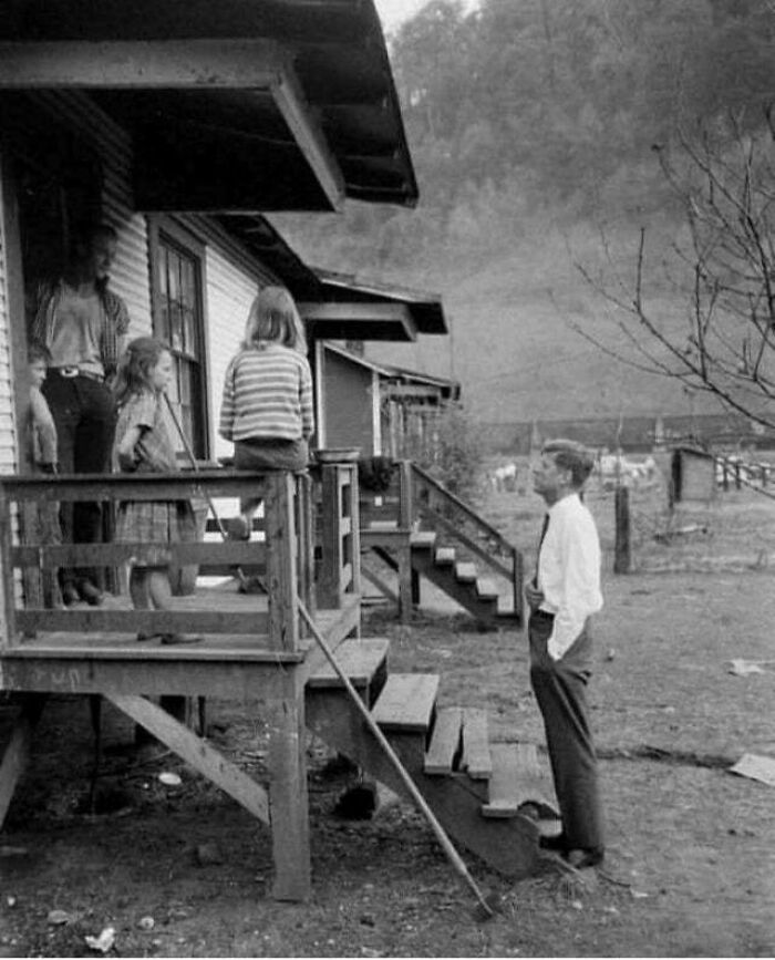 A beautiful photo from history shows children and adults gathered on a wooden porch, looking out at a rural landscape.