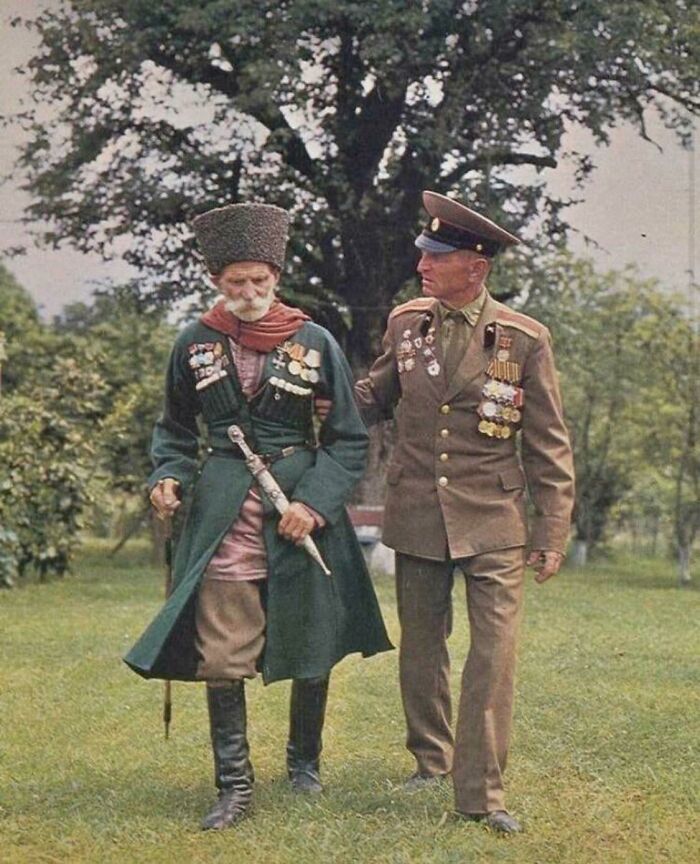 An interesting photo from history of two men, one in traditional attire and the other in a military uniform, walking together.