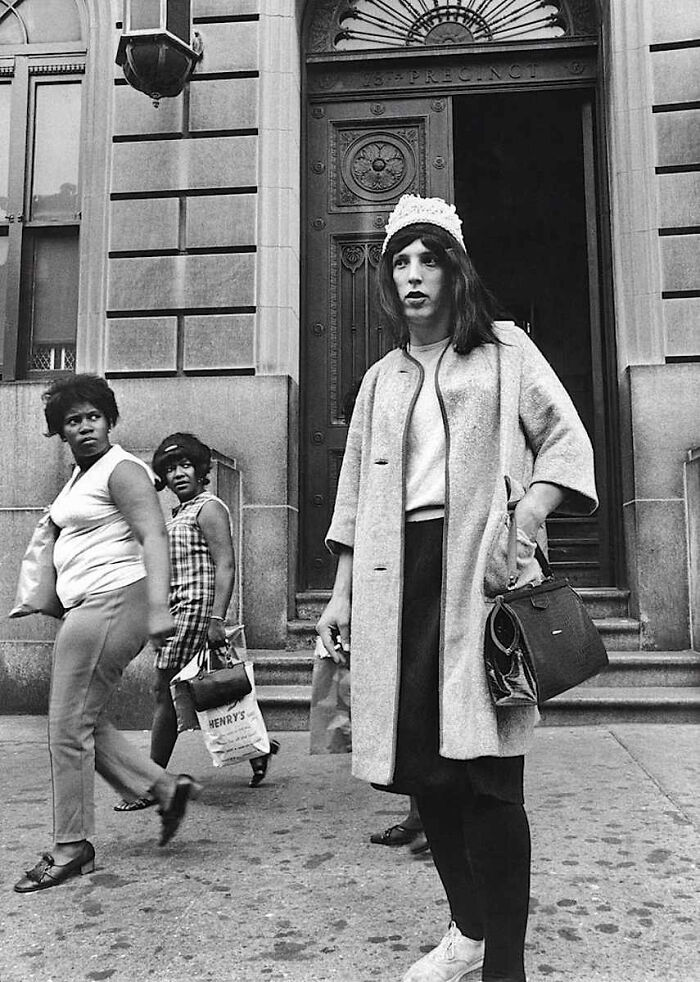 A black and white photo of people on a city street, capturing a candid and interesting moment in history.