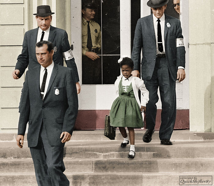 Ruby Bridges, a young African American girl, is escorted by US Marshals during school desegregation in an iconic moment from history.