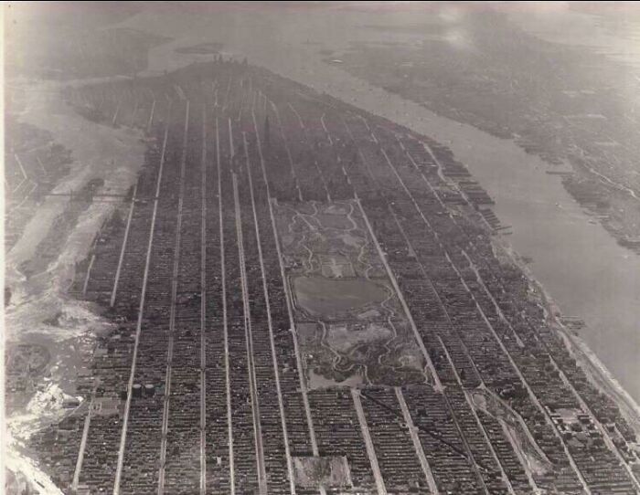 An aerial view of a sprawling city, crisscrossed with streets and featuring a central park, an interesting photo from history.