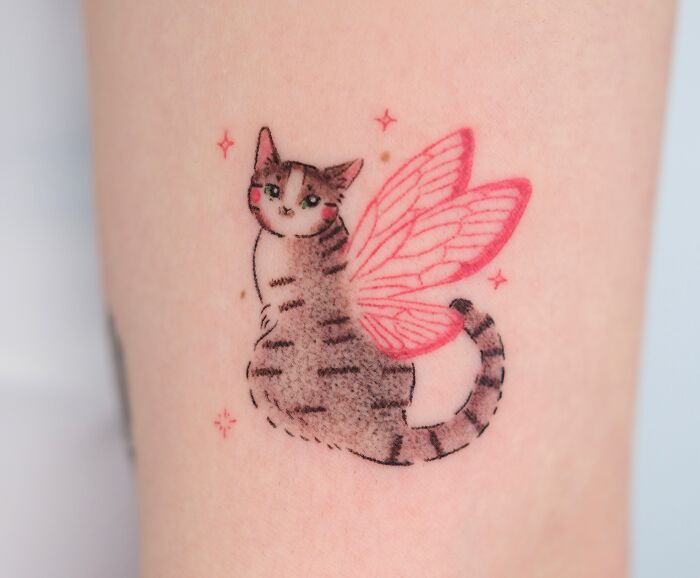 Charming cat with pink wings tattoo, reminiscent of a crayon drawing, expressing childhood creativity.