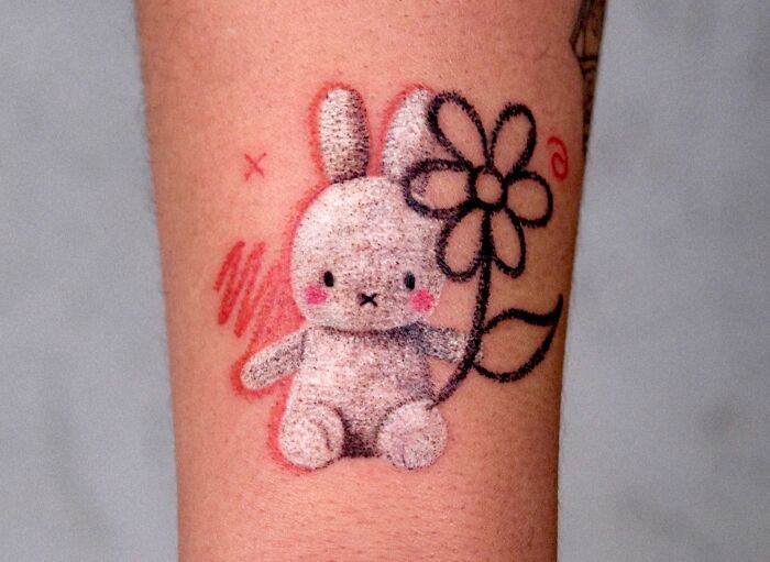 Charming crayon drawing-inspired tattoo of a plush bunny holding a flower, evoking childhood creativity.