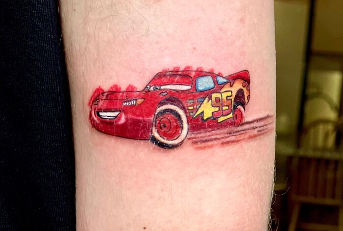 Lightning McQueen car tattoo with a crayon drawing style on an arm.