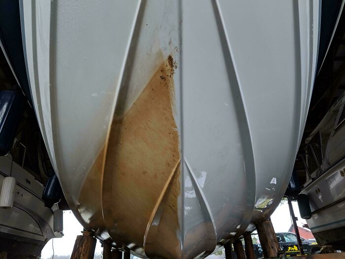 Boat hull before and after power washing, revealing a clean, white surface beneath the marine grime.