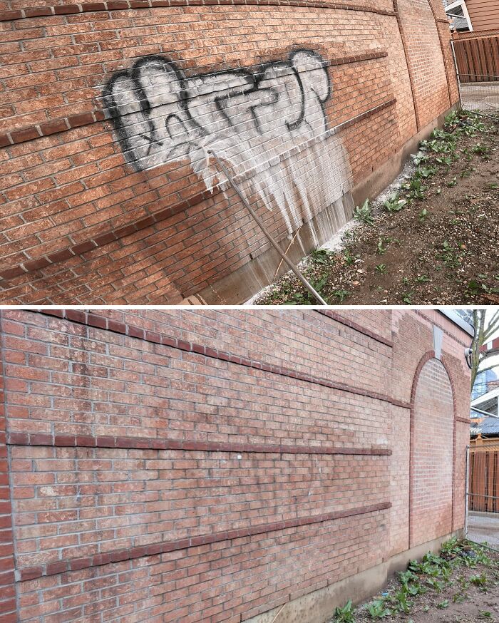 Power washing graffiti off a brick wall, restoring the clean, original brickwork.