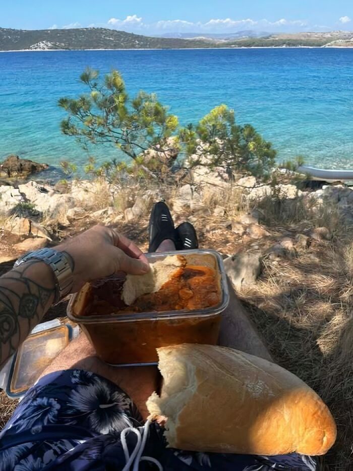 A person eating a meal with bread by the sea, showcasing why people from Eastern Europe are built different.