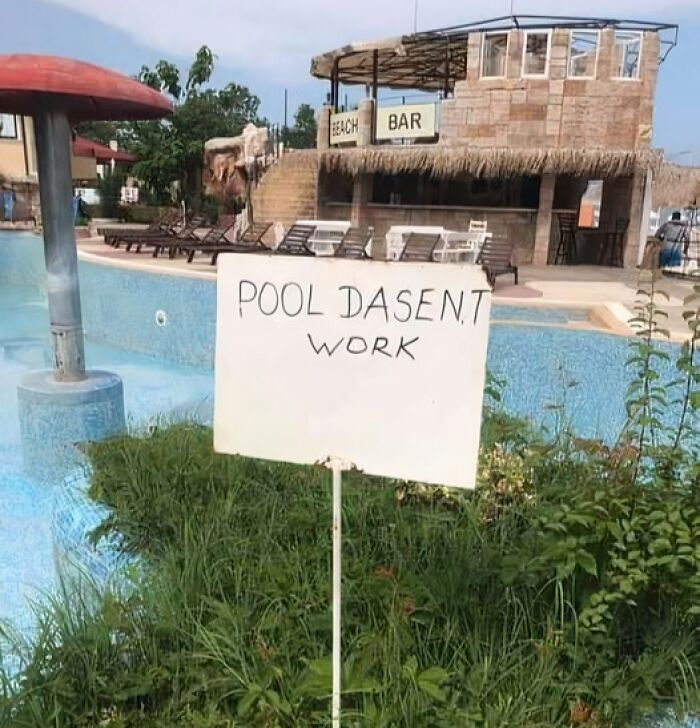 A sign saying POOL DASENT WORK next to an empty swimming pool at a resort, an amusing Eastern European moment.