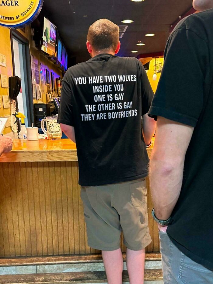 A man wearing a black T-shirt with a humorous message about two wolves inside, providing random jokes and laughs.