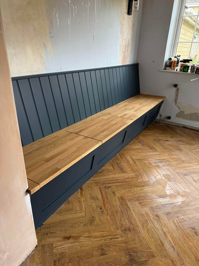 An amazing home renovation featuring a newly built, long dark-paneled bench with a light wooden top in a room.