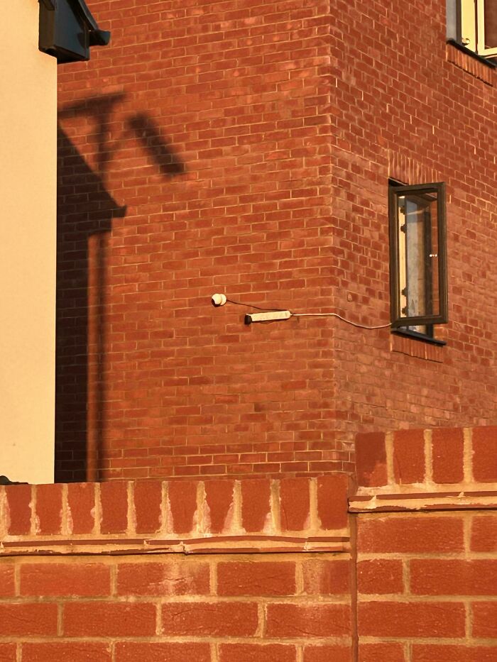 An exterior view of a home renovation, highlighting people putting time and effort into their homes. The image shows a brick wall with a shadow, emphasizing the structural changes.