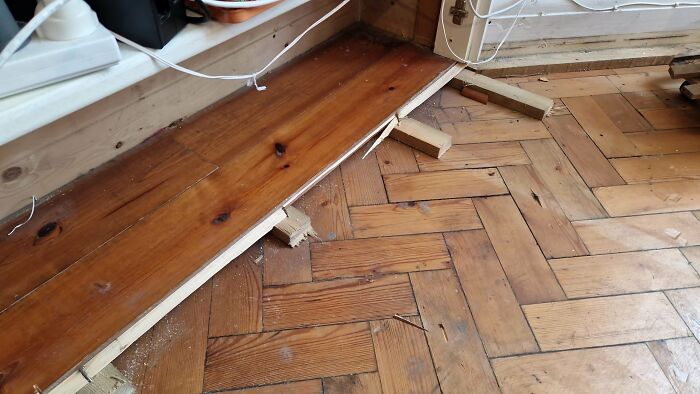 Close-up of old wooden parquet flooring being renovated in a home, showcasing the restoration process.