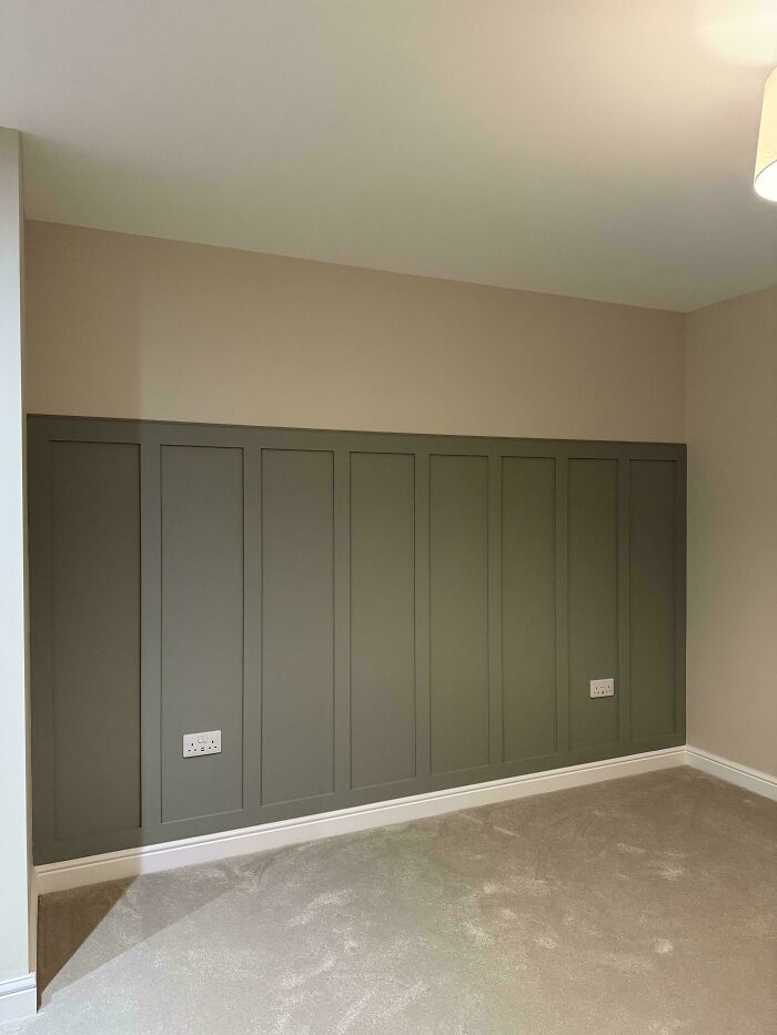 A newly renovated room featuring dark green wall paneling, highlighting home renovations by owners.