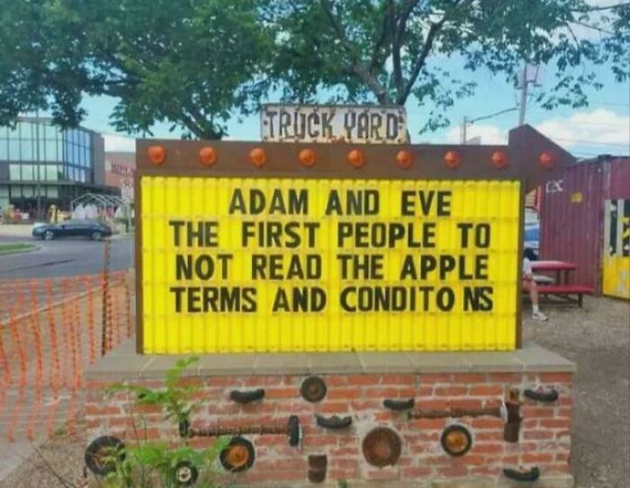 A sign outside a business with a funny joke about Adam and Eve not reading Apple terms, perfect for random jokes.