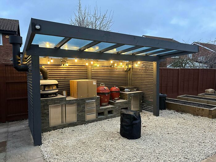 Outdoor kitchen setup with grilling station under a modern pergola, highlighting home renovation efforts.