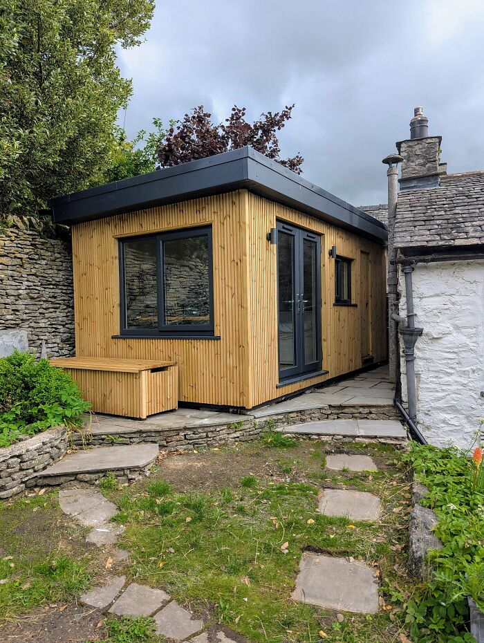 Stylish backyard shed with wooden paneling and dark window frames, an amazing home renovation project.