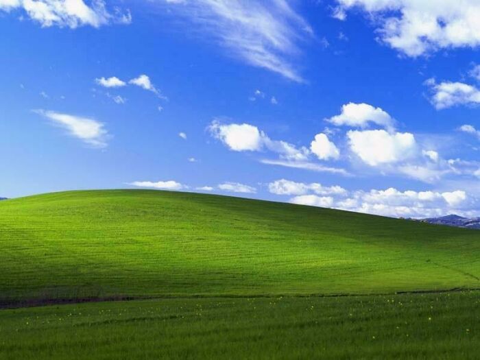 A vibrant green hill under a blue sky with clouds, representing the old internet background Bliss for Windows XP.