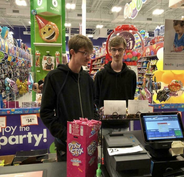 Two young men working at a Party City store checkout, surrounded by party supplies, a fascinating find from the internet.