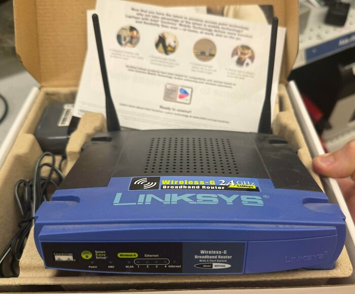 An image of an Old Internet Linksys Wireless-G 2.4 GHz Broadband Router with antennas, still in its box.